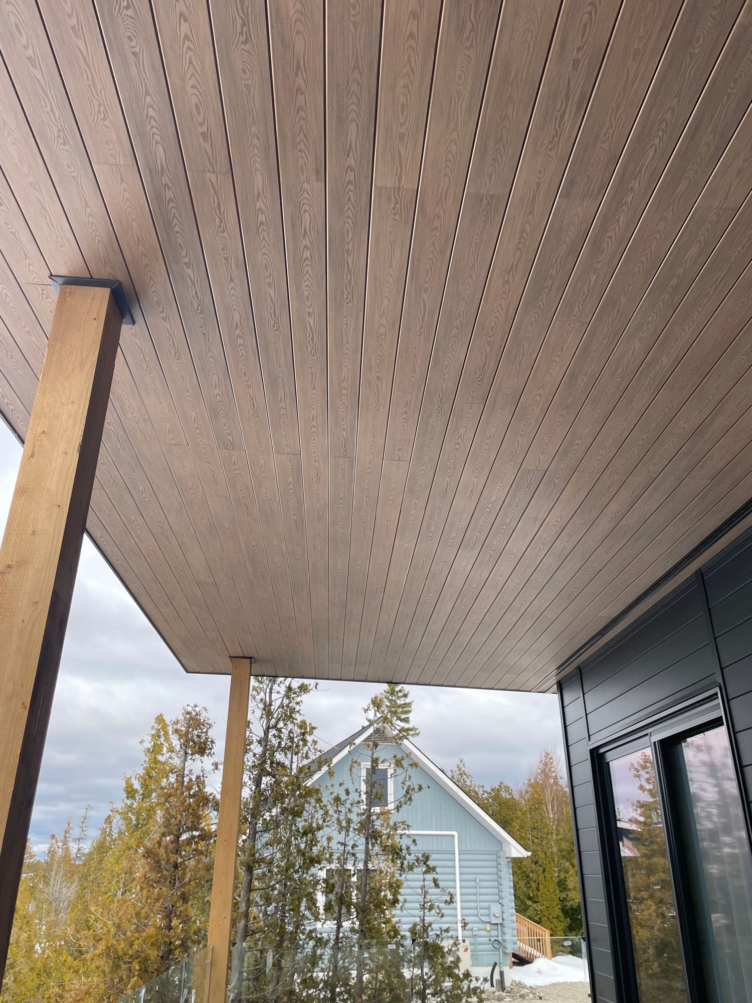 Walnut SoffiWood porch ceiling with a continuous black vent line along the wall in Sauble Beach, Ontario